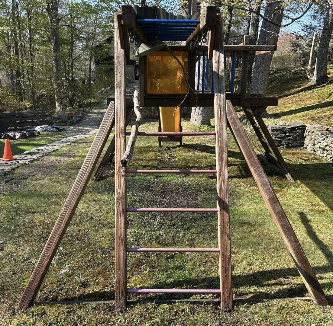 Backyard wooden playground covered in lichen and weathered grime before pressure washing.