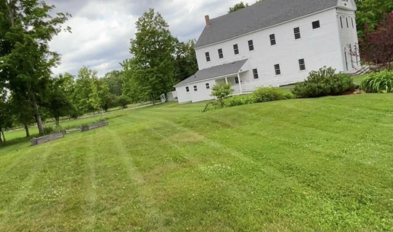 Well-maintained green lawn and historic white building cared for by Jenks Landscaping in New Salem, Massachusetts.